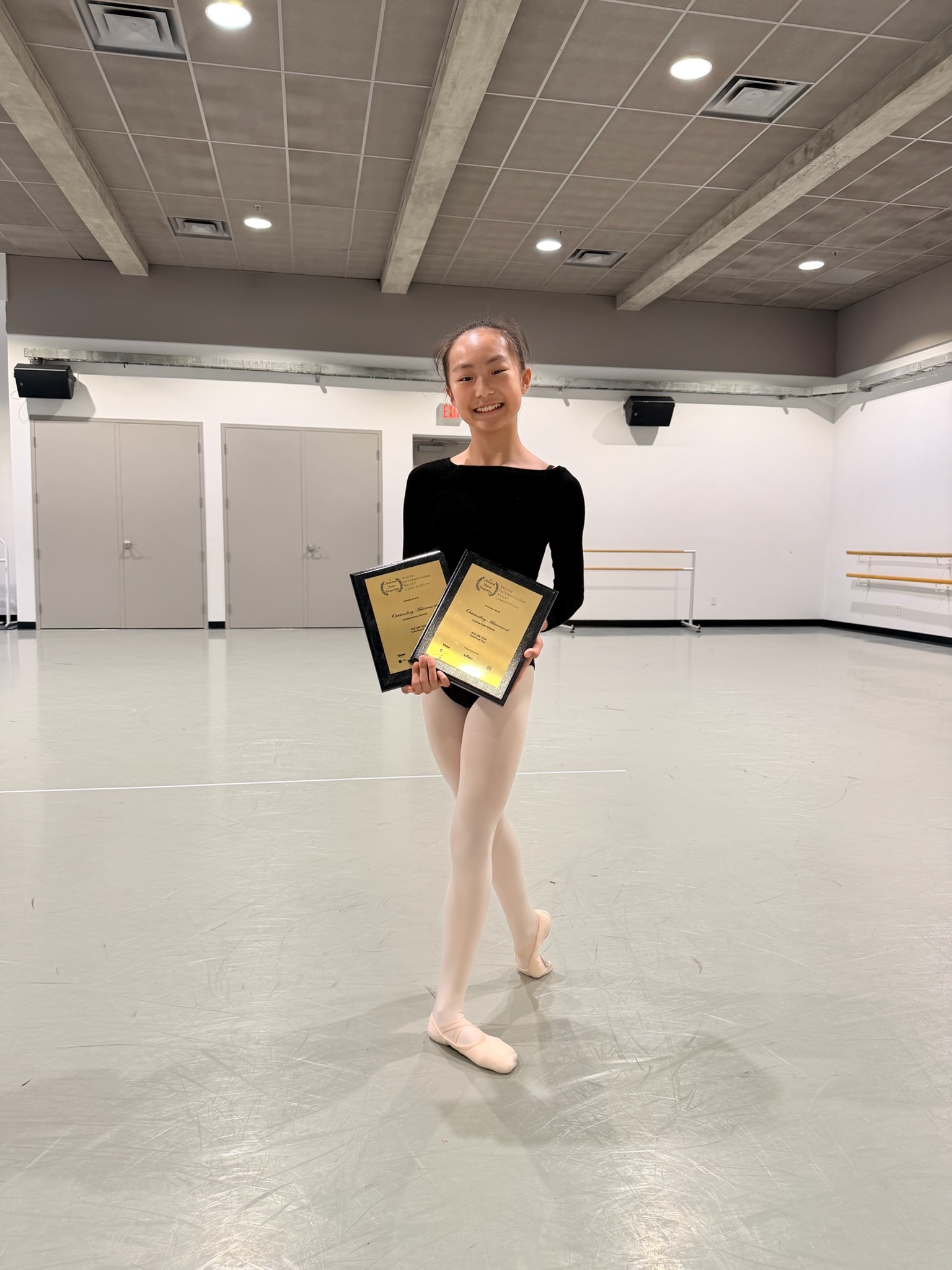 Student holding two competition awards in the studio