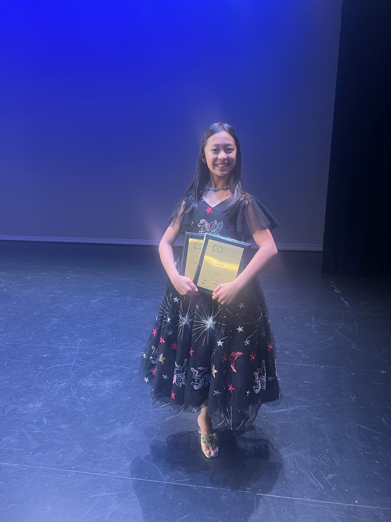 Student holding competition awards on stage